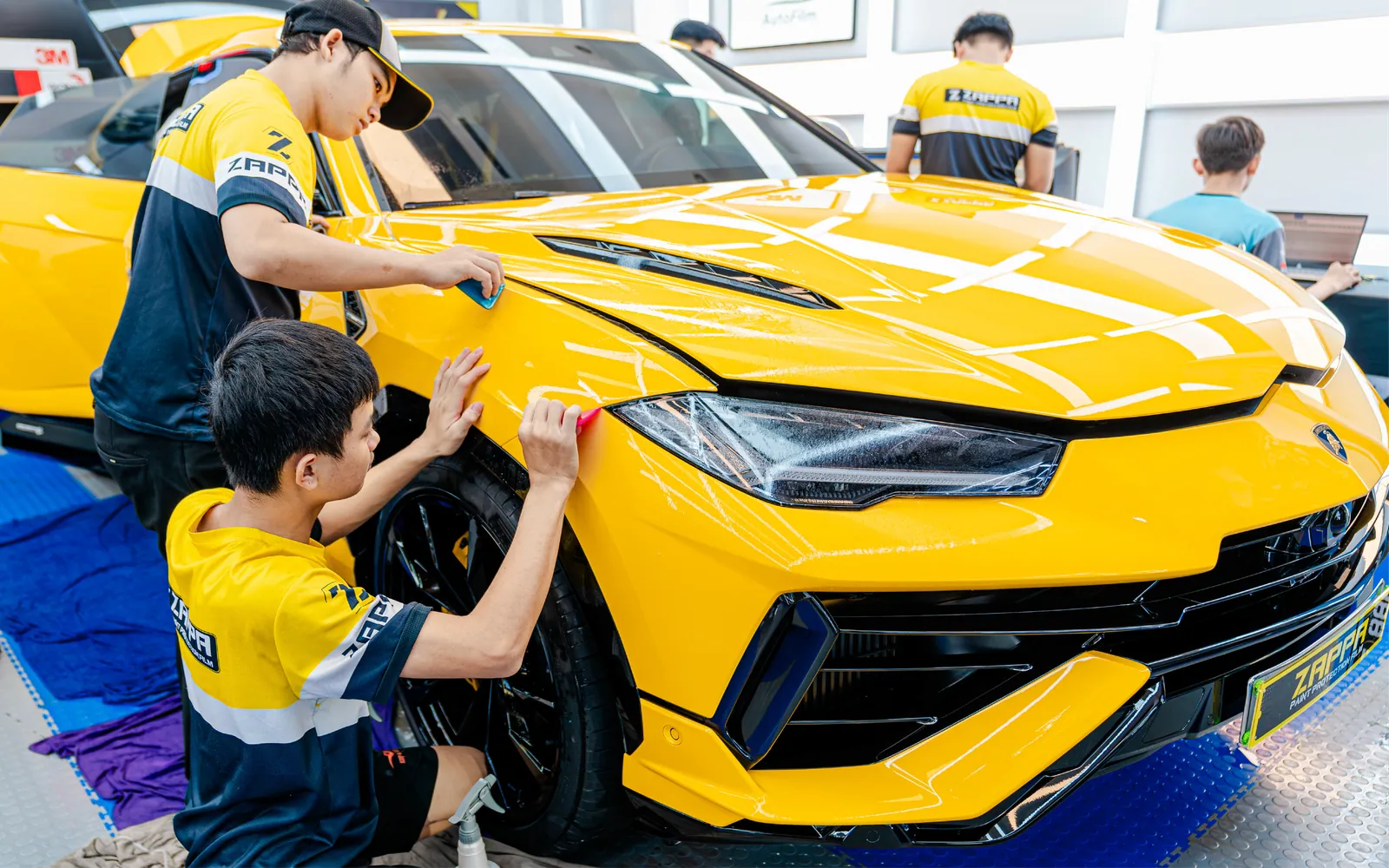 Kỹ thuật viên Store Detailing đang dán PPF cho ô tô tại phòng thi công kín ở TP.HCM